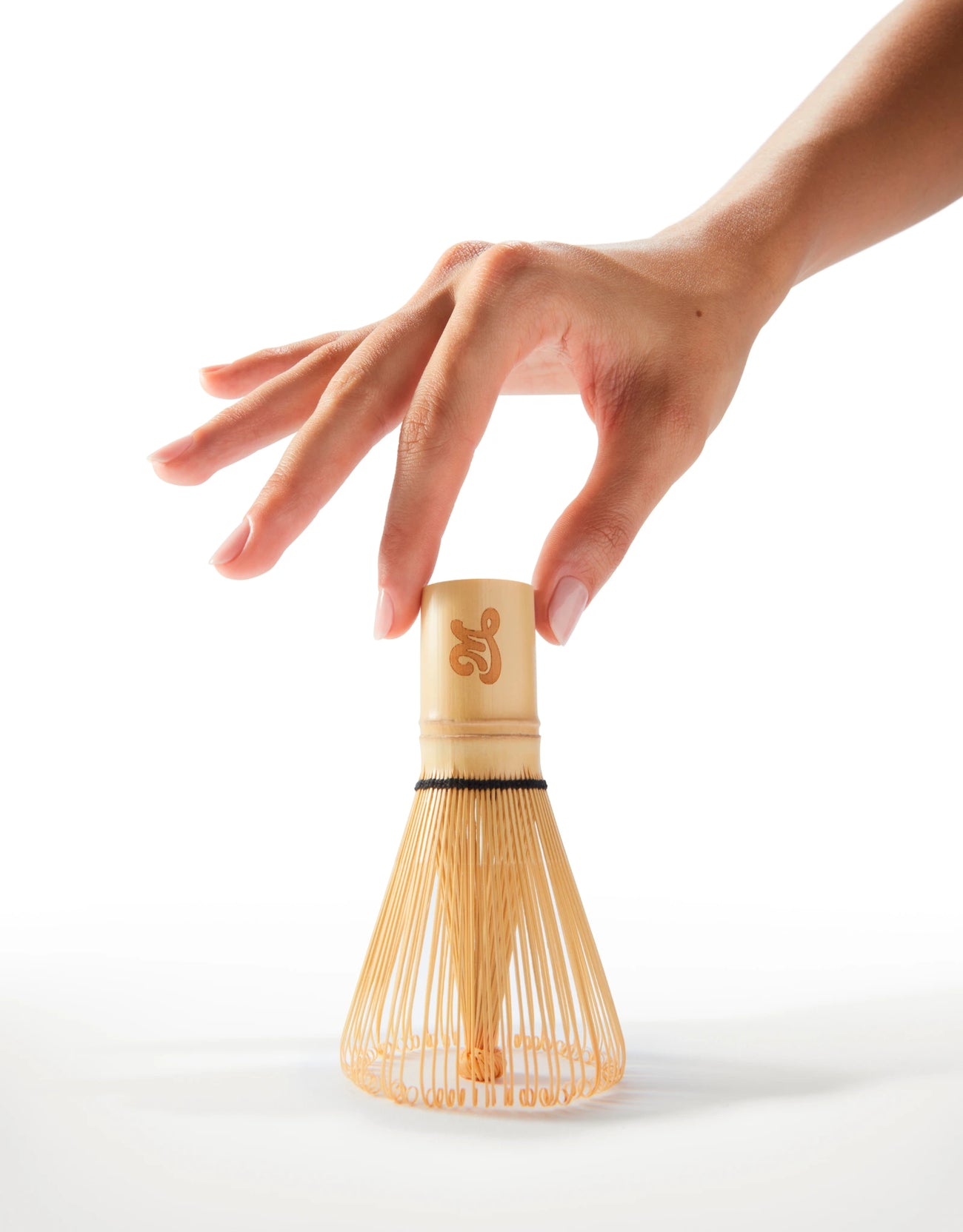 Main tenant un fouet en bambou chasen Milia Matcha sur fond blanc