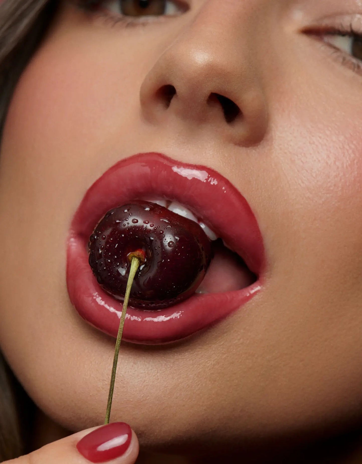 Bouche avec rouge à lèvres qui croque dans une cerise 