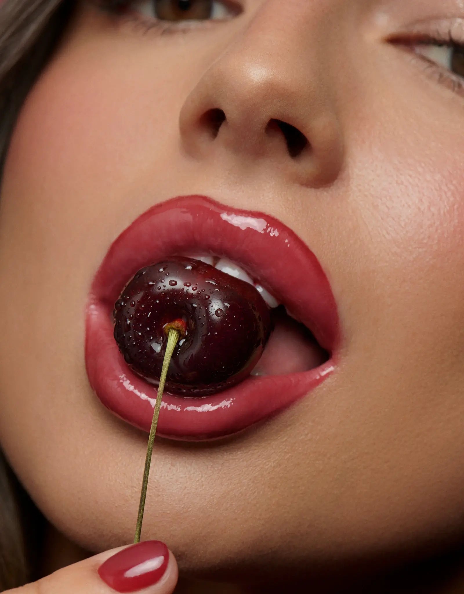 Bouche avec rouge à lèvres qui croque dans une cerise 
