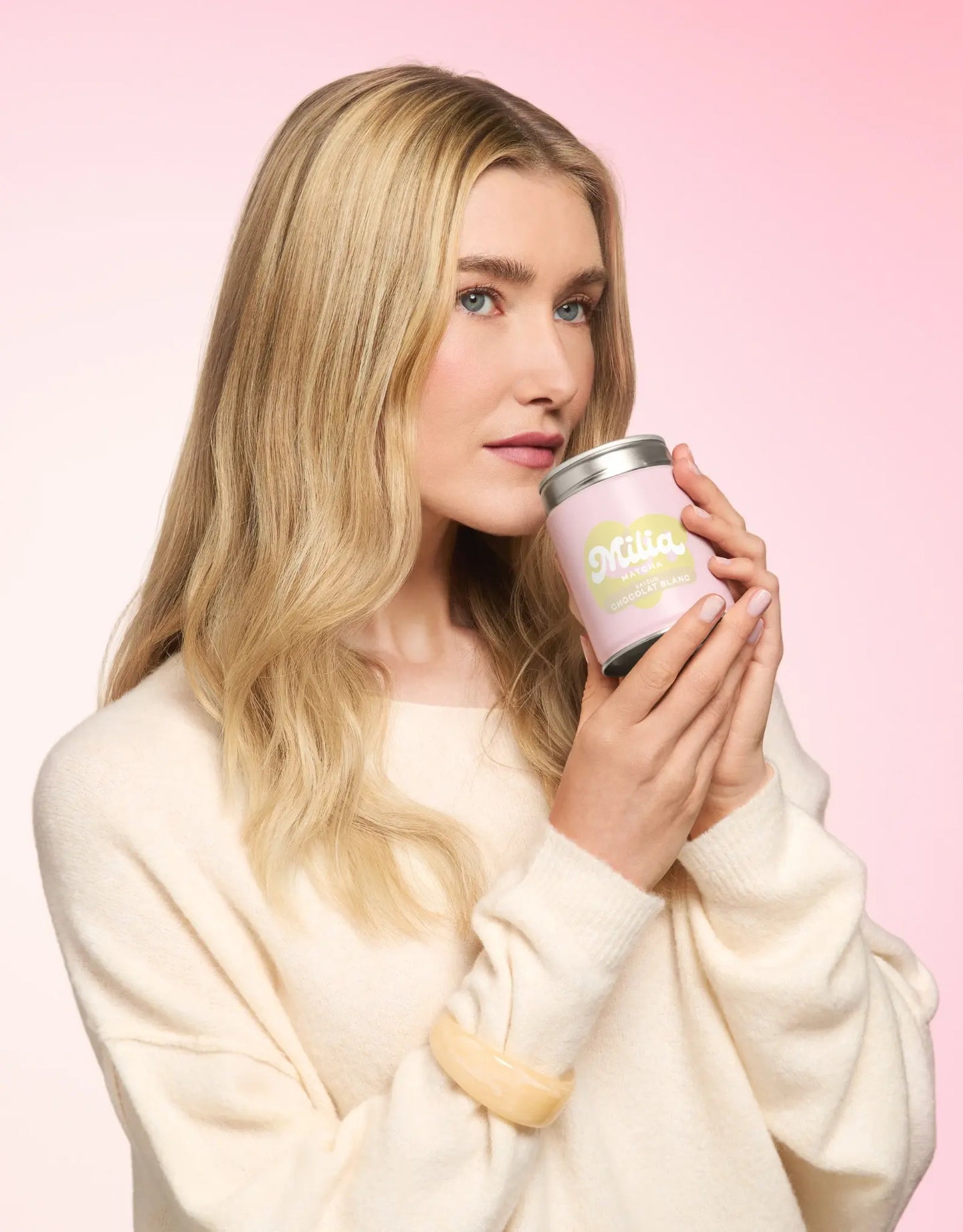 Mannequin tenant une boîte de matcha Milia Matcha saveur chocolat blanc sur fond rose