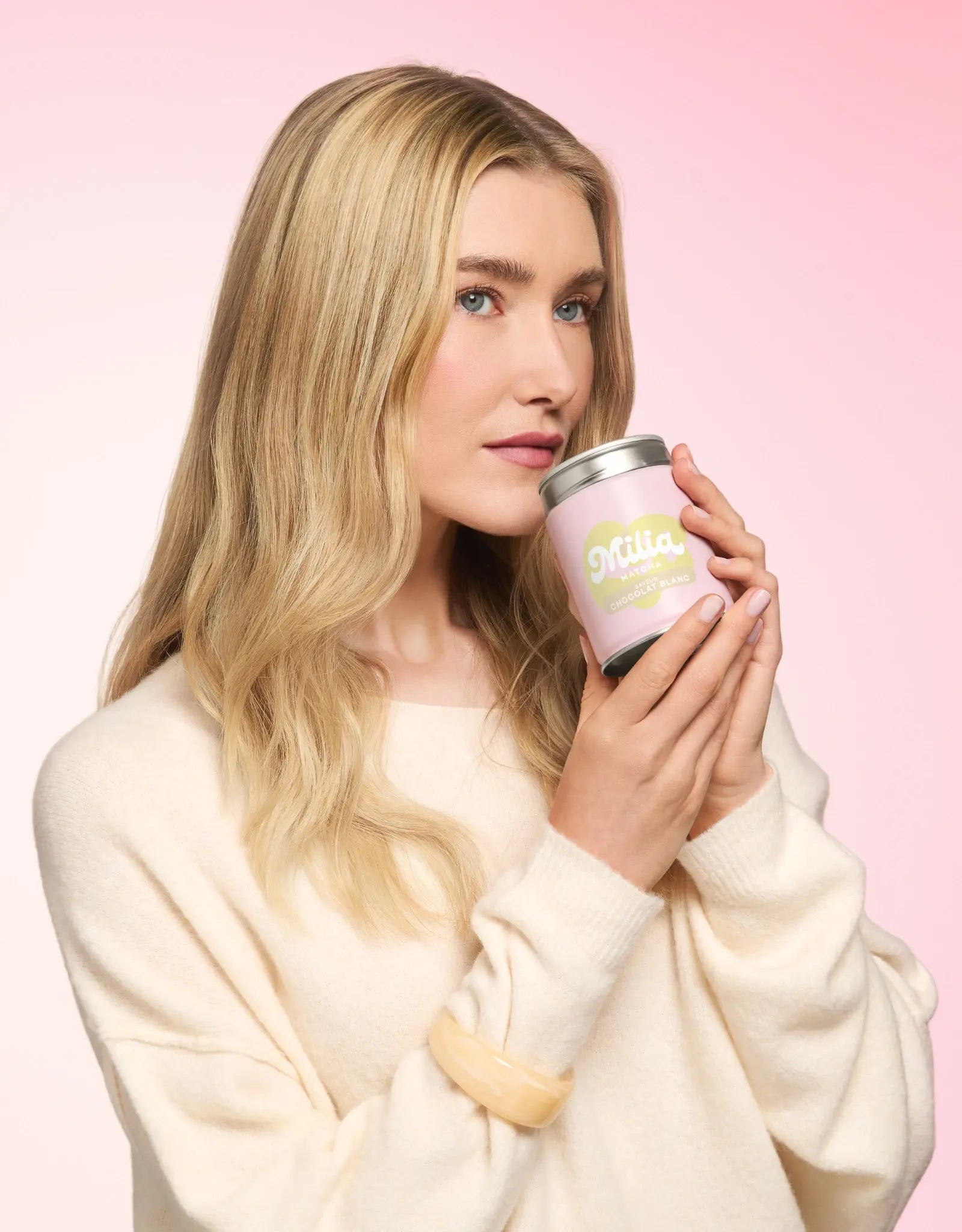 Mannequin tenant une boîte de matcha Milia Matcha saveur chocolat blanc sur fond rose