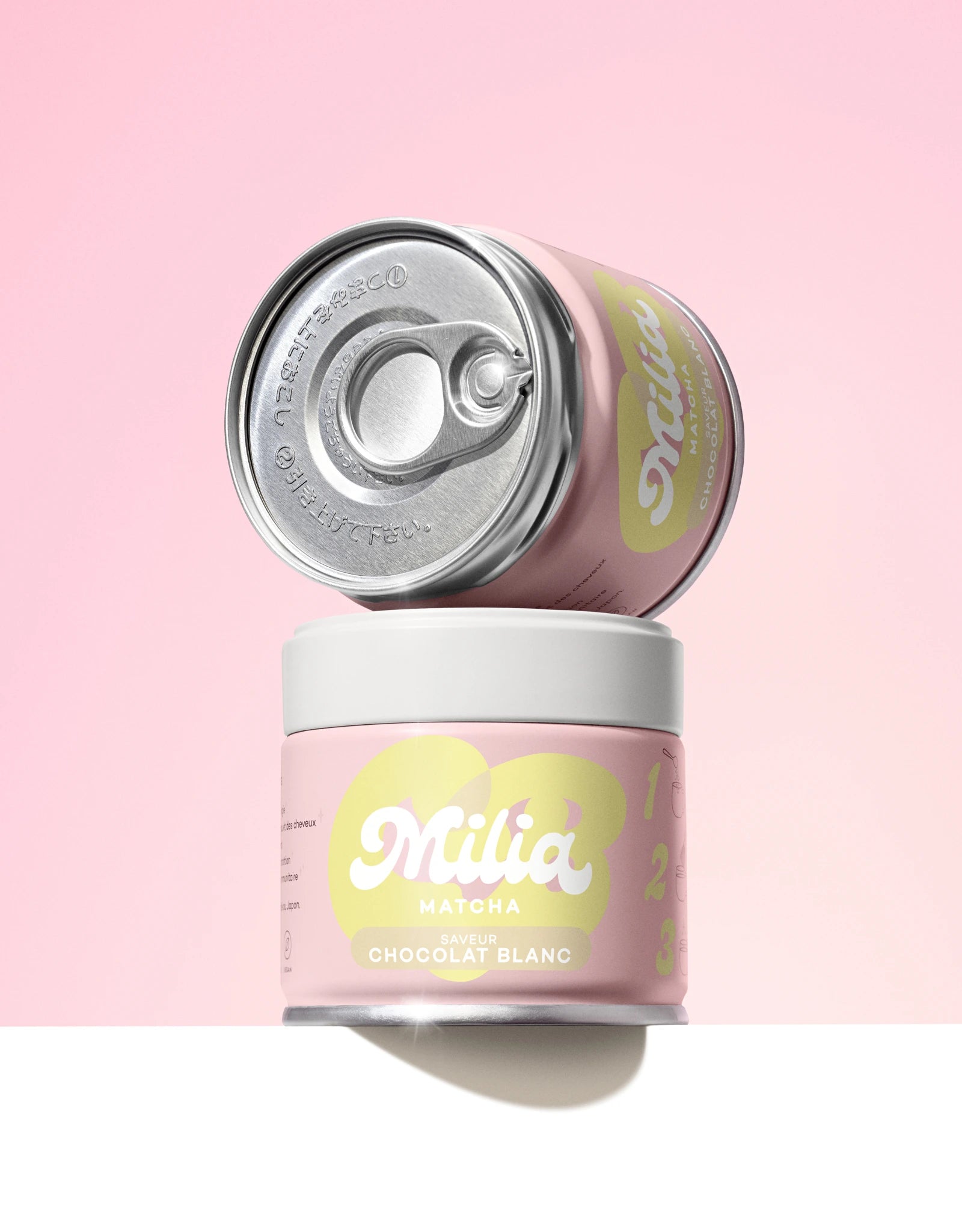 Deux canettes matcha okumidori arôme chocolat blanc sur fond rose