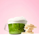 Tasse de matcha latte mousse saveur chocolat blanc et carrés de chocolat sur fond rose
